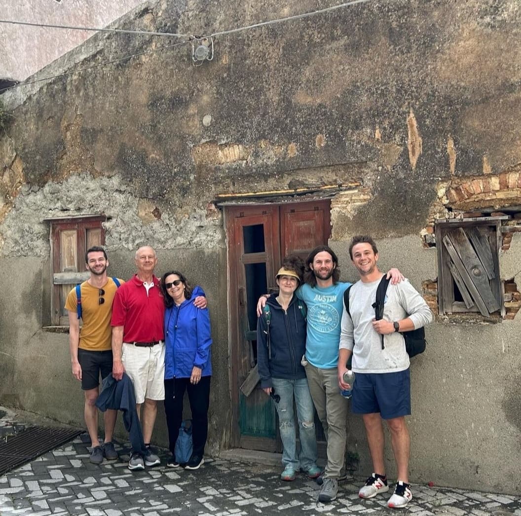 Family standing outside their ancestral home during a Sicily genealogy heritage tour in a historic Sicilian village.